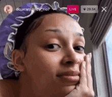 a woman wearing a purple shower cap is looking out a window and making a funny face .