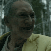 a man in a yellow jacket is smiling with his mouth open