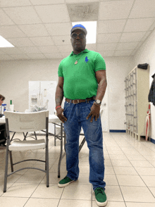 a man wearing a green polo shirt and blue jeans stands in a room