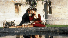 a man and a woman are kissing in front of a pond