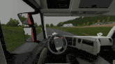 the inside of a truck with a steering wheel and a mirror