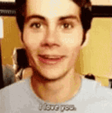 a close up of a young man 's face with the words `` i love you '' written on his shirt .