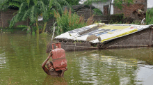 a man in a flooded area carrying a red cylinder that says fg on it