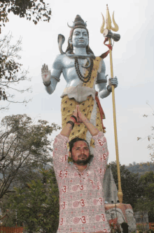 a man stands in front of a large statue of shiva with the number 3 on his shirt