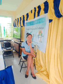 a woman sits in front of a sign for the senior high school