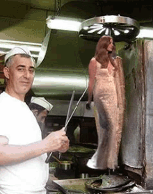 a man in a white shirt is preparing food in a kitchen with a woman in a white dress standing behind him