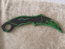 a green and black knife is sitting on a towel on a bed .