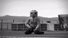 a black and white photo of a robot with a box on his head