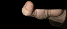 a close up of a person 's thumb with a black background