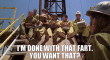 a group of men are sitting on top of a wooden platform and a man is standing in the background .
