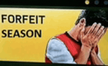a man is covering his face with his hands in front of a yellow sign that says `` forfeit season '' .