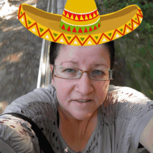 a woman wearing glasses and a sombrero is taking a selfie