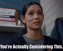 a woman says " you 're actually considering this " in front of a stack of books