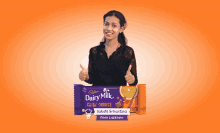 a woman is giving a thumbs up next to a bar of dairy milk chocolate