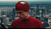 a man in a spiderman costume is holding a sword in front of a city skyline