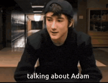 a young man wearing a baseball cap is talking about adam .