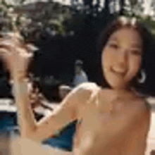 a woman in a bikini is standing next to a swimming pool .