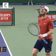 a man in a red shirt is holding a tennis racquet on a tennis court with an emirates better sign in the background