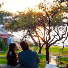 a man and a woman are sitting on a ledge looking at the sunset with the words thateclipse below them