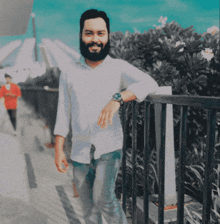 a man with a beard is leaning against a railing and smiling