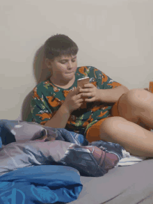 a boy laying on a bed looking at his cell phone