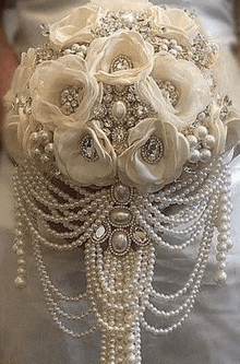 a close up of a bride holding a bouquet of pearls and flowers .