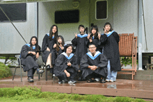 a group of graduates pose for a picture in front of a trailer