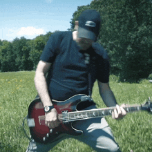 a man is playing a guitar in a field with trees in the background and a watch on his wrist