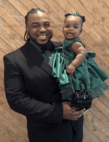 a man in a suit is holding a little girl in a green dress