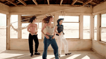 three women are dancing in an empty room with one wearing a shirt that says ' i love you '