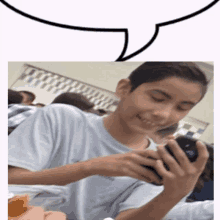 a boy is smiling while looking at his phone with a speech bubble above him