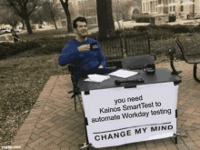 a man sitting at a desk with a sign that says change my mind