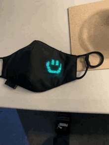 a black face mask with a green smiley face on it