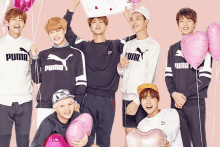 a group of young men wearing puma sweatshirts are posing with pink balloons