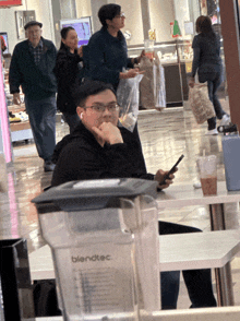 a man sits at a table with a blendtec pitcher