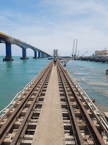 a bridge over a body of water with a man walking on the tracks