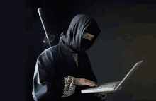 a man in a ninja costume is holding a laptop