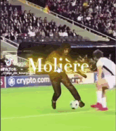 a man is kicking a soccer ball on a field in front of a crowd while another man watches .