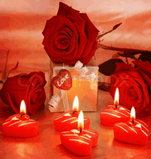 a heart with the word love on it sits next to candles and roses