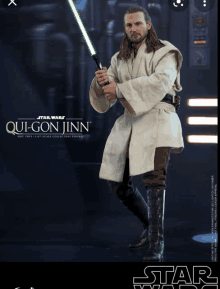 a star wars figurine of qui-gon jinn is holding a green lightsaber