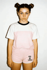 a girl wearing a pink and white t-shirt and shorts with the word winds embroidered on her shorts