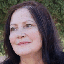 a close up of a woman 's face with dark hair and green eyes