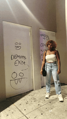 a woman is standing in front of a door that has demons exist written on it