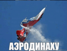 a red , white and blue fighter jet is flying through a blue sky with smoke coming out of the tail .