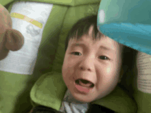 a baby in a green stroller is crying