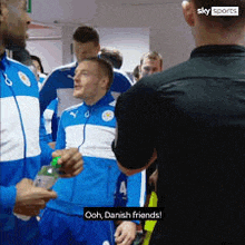 a group of men in blue and white jackets are standing next to each other and one of them is saying ooh danish friends .