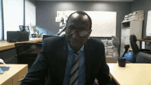 a man in a suit and tie is sitting at a desk in an office