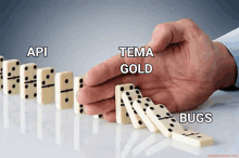 a hand is holding a row of dominoes with the words api tema gold and bugs visible