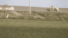 a car is driving down a road next to a field