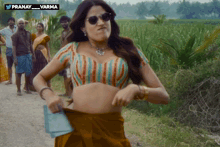 a woman in a striped blouse and sunglasses is standing in a field